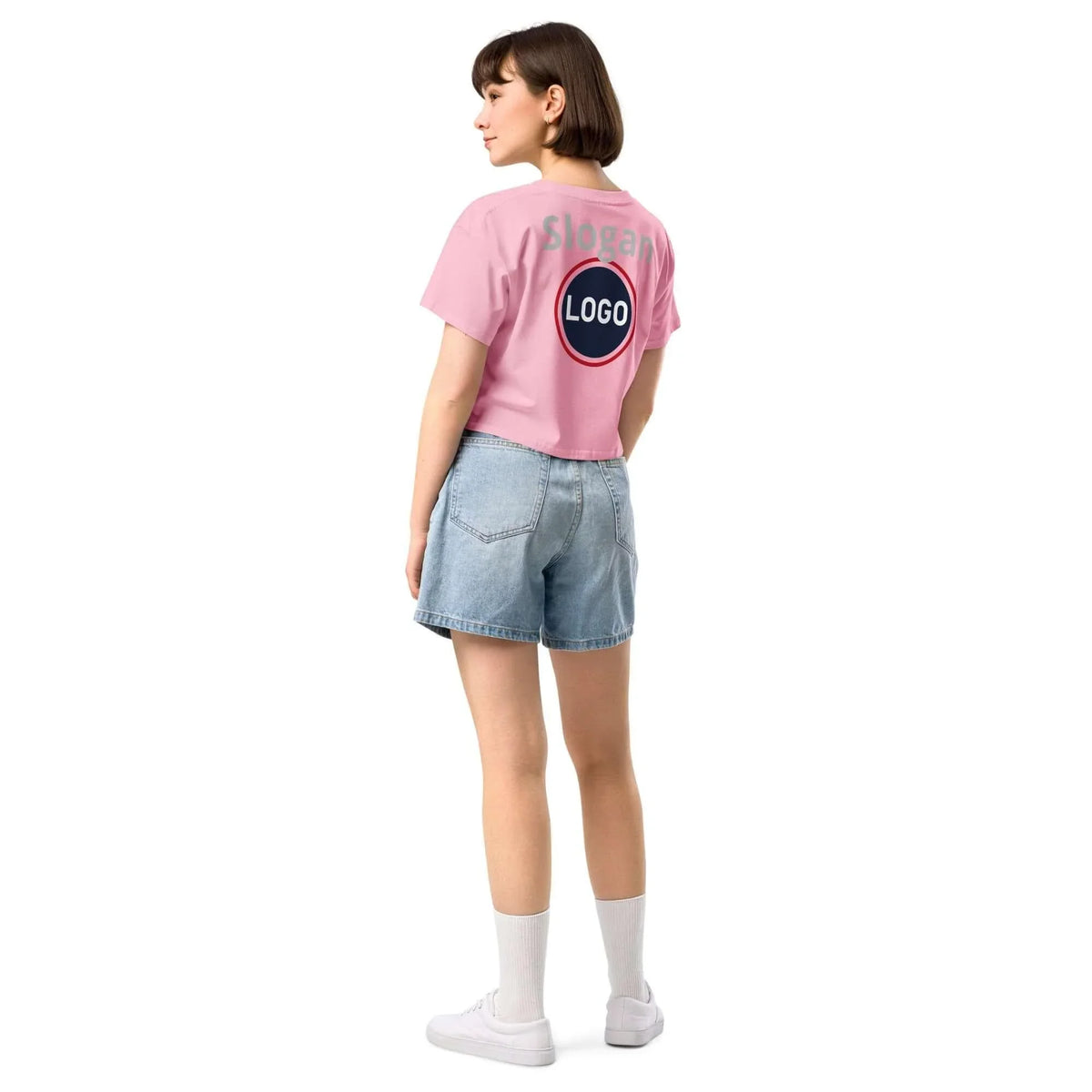 Frau von hinten in rosa T-Shirt mit Logo-Print, Jeans-Shorts und weißen Sneakern