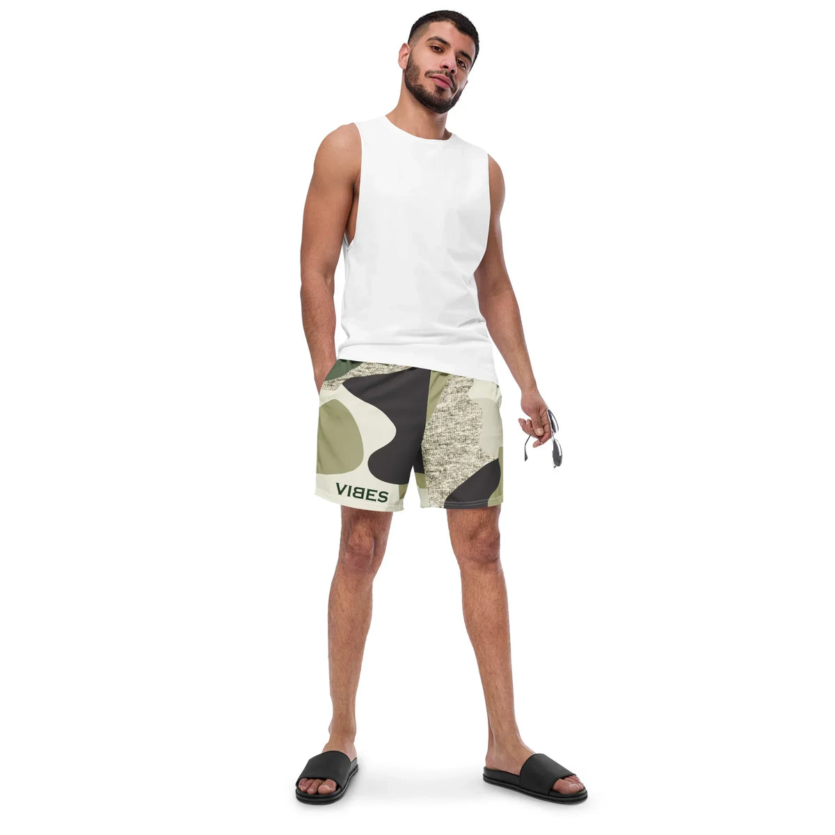 Mann trägt weiße Tanktop und CREWILD Badeshorts im Camouflage-Design mit VIBES-Schriftzug.