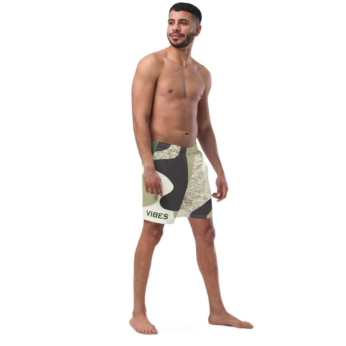 Mann trägt CREWILD Badeshorts mit Camouflage-Muster in Grün- und Beigetönen