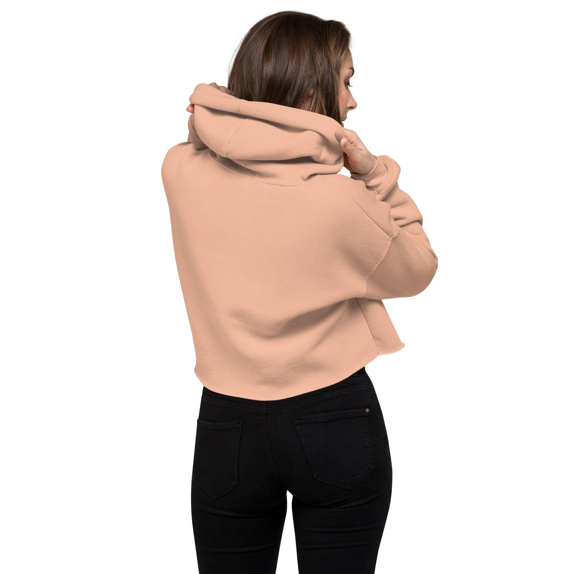 Frau mit rosa Crop Hoodie und schwarzer Jeans von hinten vor weißem Hintergrund