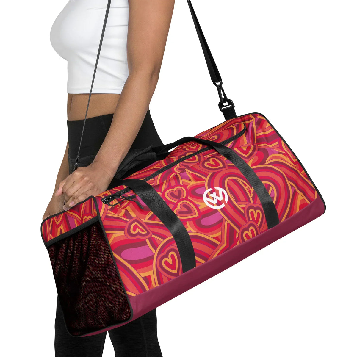 Person trägt eine personalisierte Sporttasche mit buntem, psychedelischem Muster in Rot- und Pinktönen.