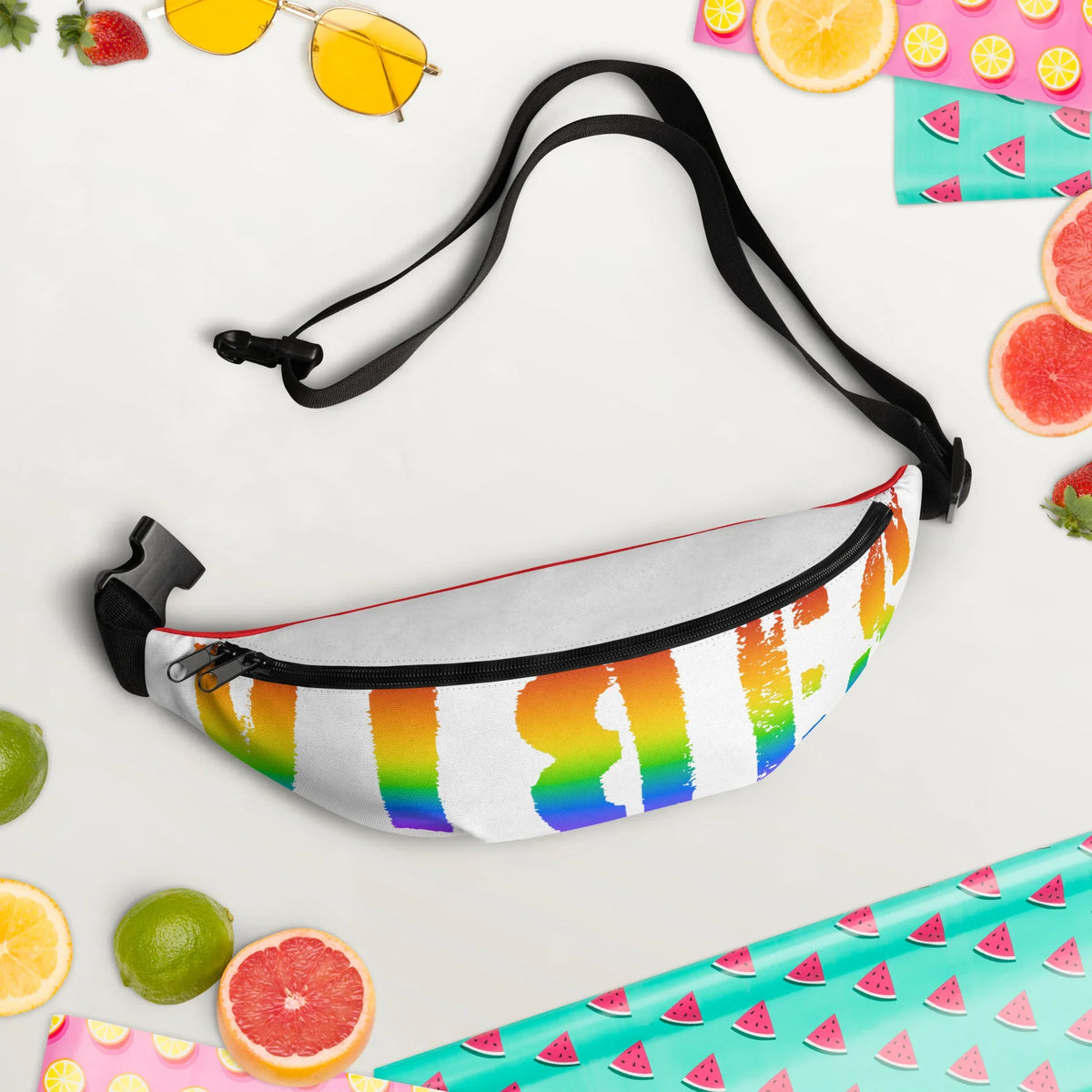 Weiße Bauchtasche mit buntem Regenbogen-Print, umgeben von Sommerfrüchten.