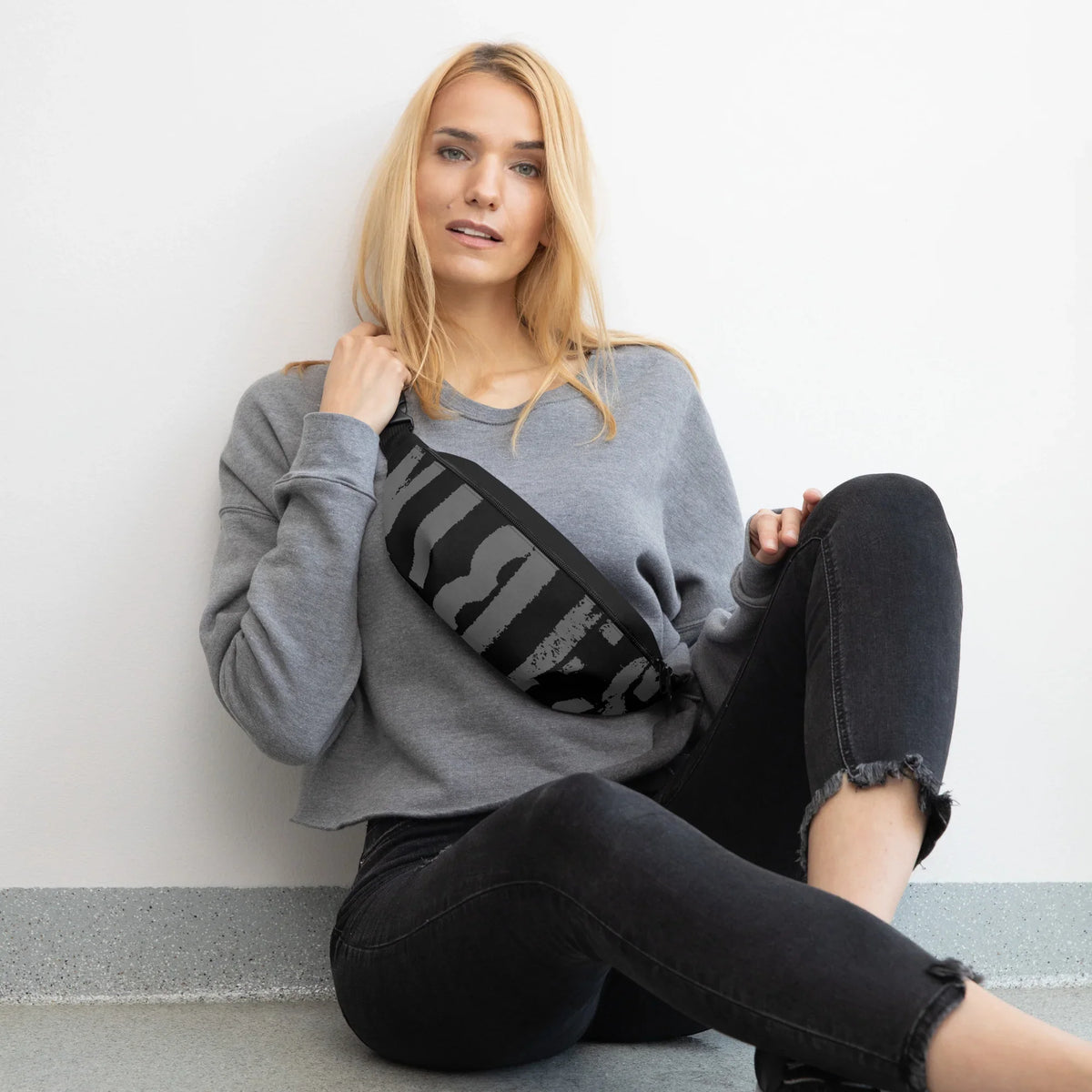 Frau in grauem Sweatshirt mit schwarz-grau gestreifter Gürteltasche