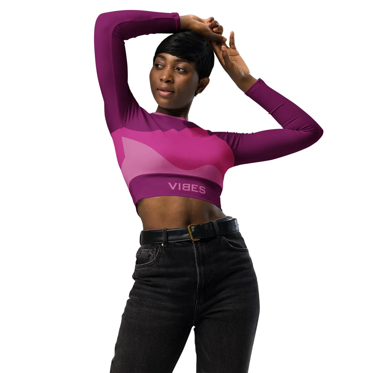 Frau im CREWILD Langarm Crop-Top mit abstraktem Pink-Design und schwarzen Jeans.
