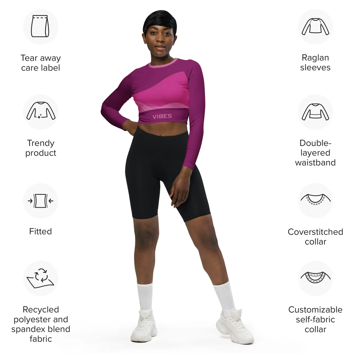 Frau trägt CREWILD Langarm Crop-Top in Pink und Schwarz mit Produktmerkmalen.