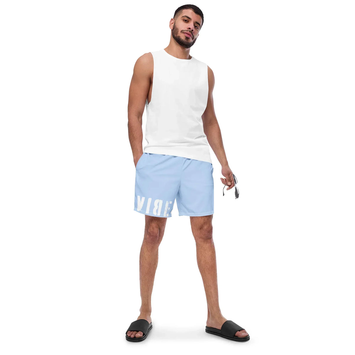 Mann trägt hellblaue CREWILD Badeshorts und weißes Tanktop vor weißem Hintergrund.