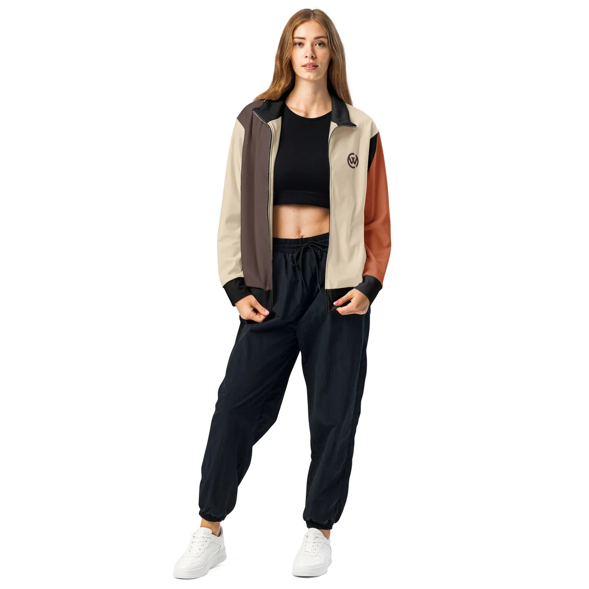 Frau trägt eine CREWILD Jacke in Braun und Creme mit schwarzen Jogginghosen und weißen Sneakern.