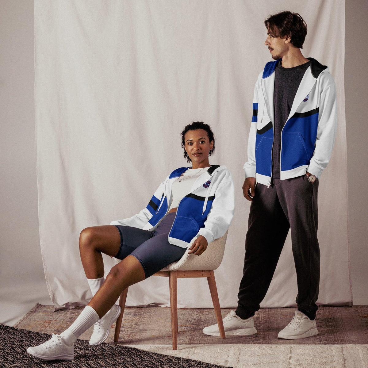 Mann und Frau in weiß-blauen ICA Zip Hoodies von CREWILD vor hellem Hintergrund.