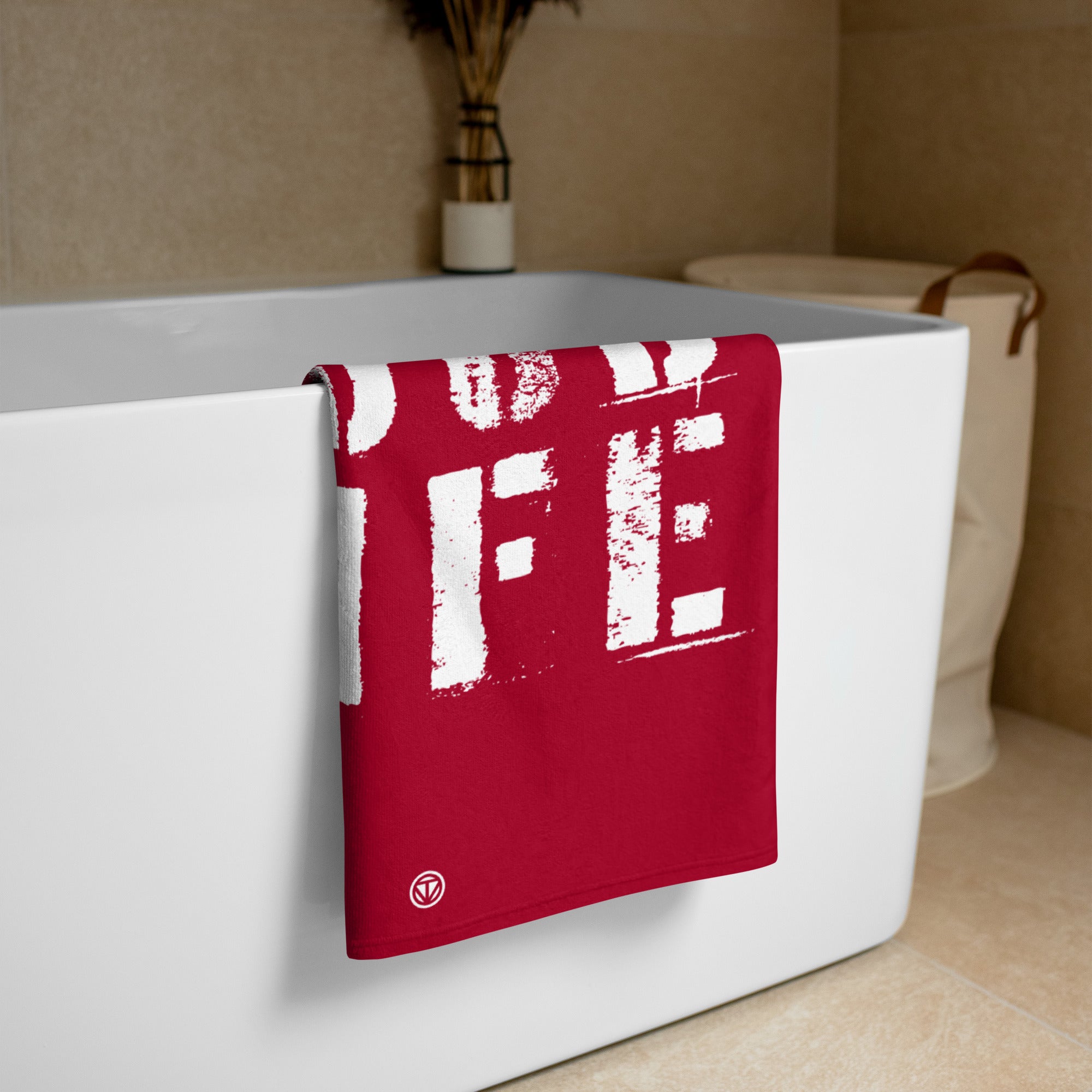 Rotes Strandtuch mit weißem Aufdruck an moderner Badewanne in neutralem Badezimmer