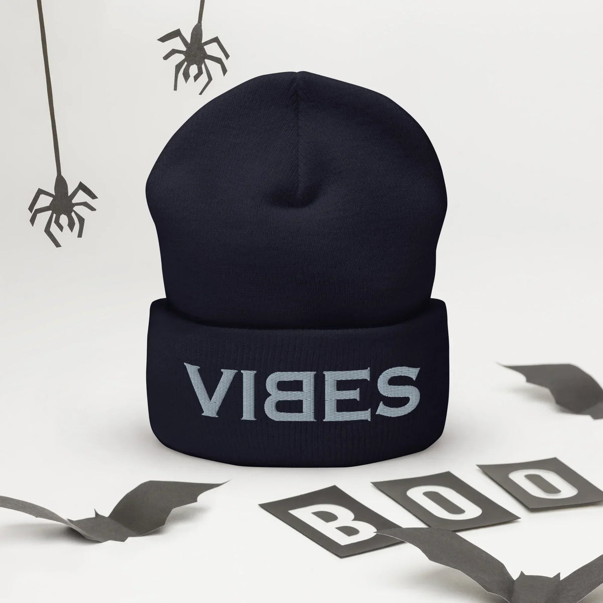 Dunkelblaue CREWILD Beanie Mütze mit grauem VIBES-Stickerei-Schriftzug und Halloween-Dekoration.