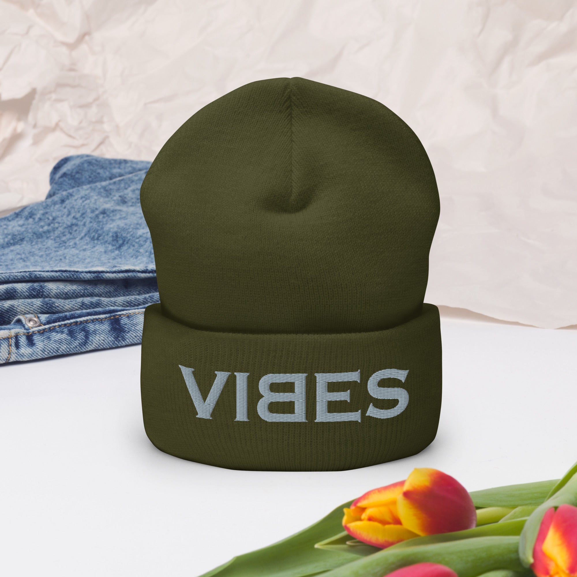 Olivegrüne CREWILD Beanie Mütze mit grauem VIBES Stick auf weißem Hintergrund