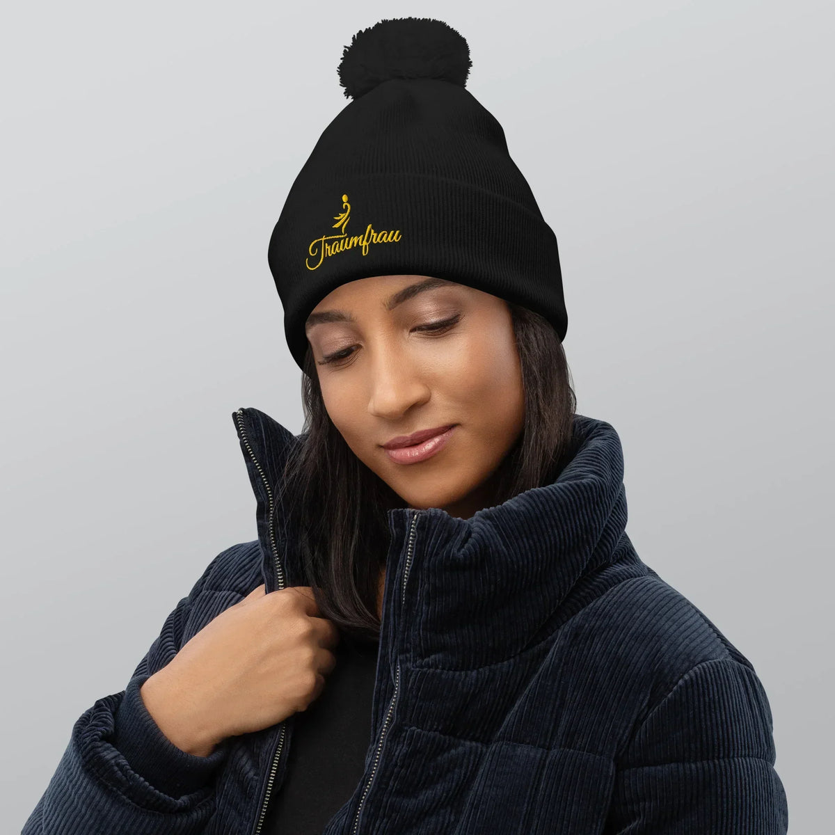 Frau trägt schwarzen CREWILD Bommel-Beanie mit gelbem &