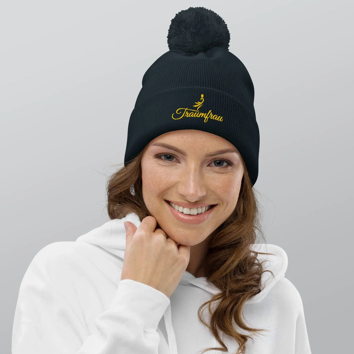 Frau trägt eine schwarze CREWILD Bommel-Beanie mit gelbem &