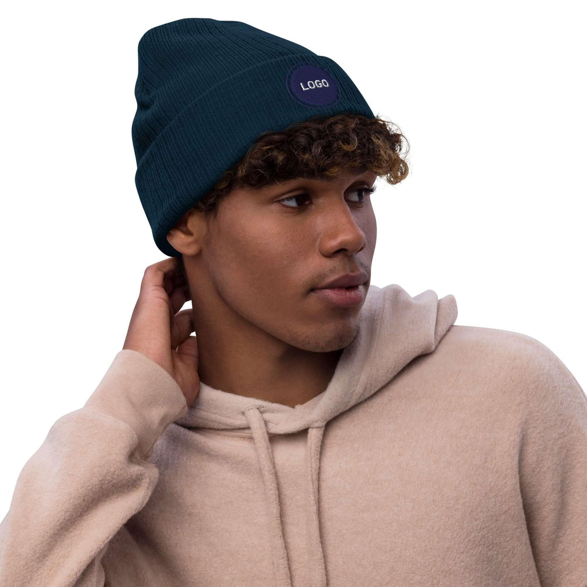 Person trägt eine dunkelblaue Beanie-Mütze und einen beigen Hoodie.