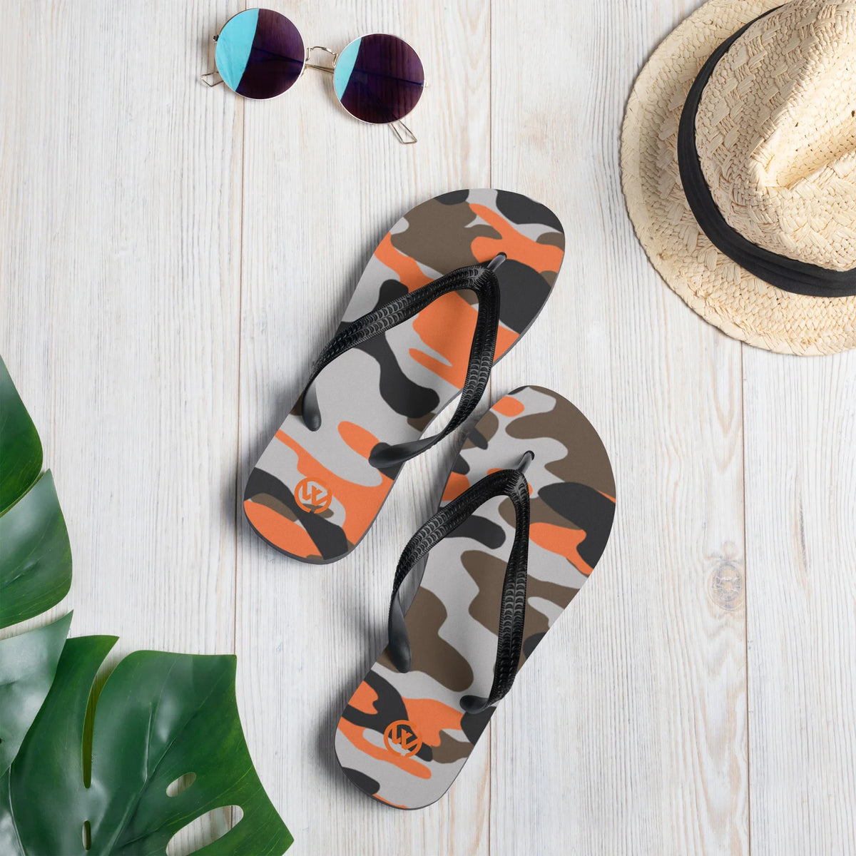 CREWILD Flip-Flops im orange-grauen Camouflage-Design auf hellem Holzhintergrund.