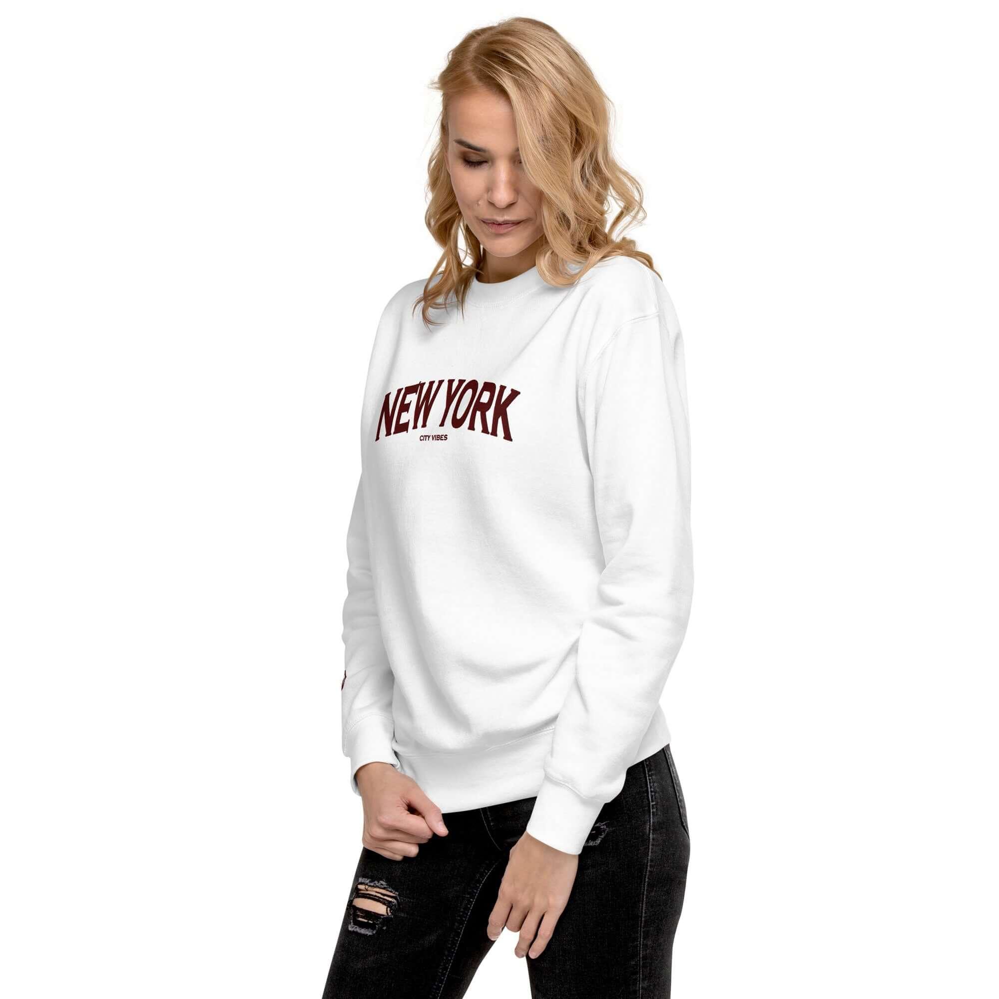 Frau in weißem Sweatshirt mit rotem New York Aufdruck und schwarzer Jeans