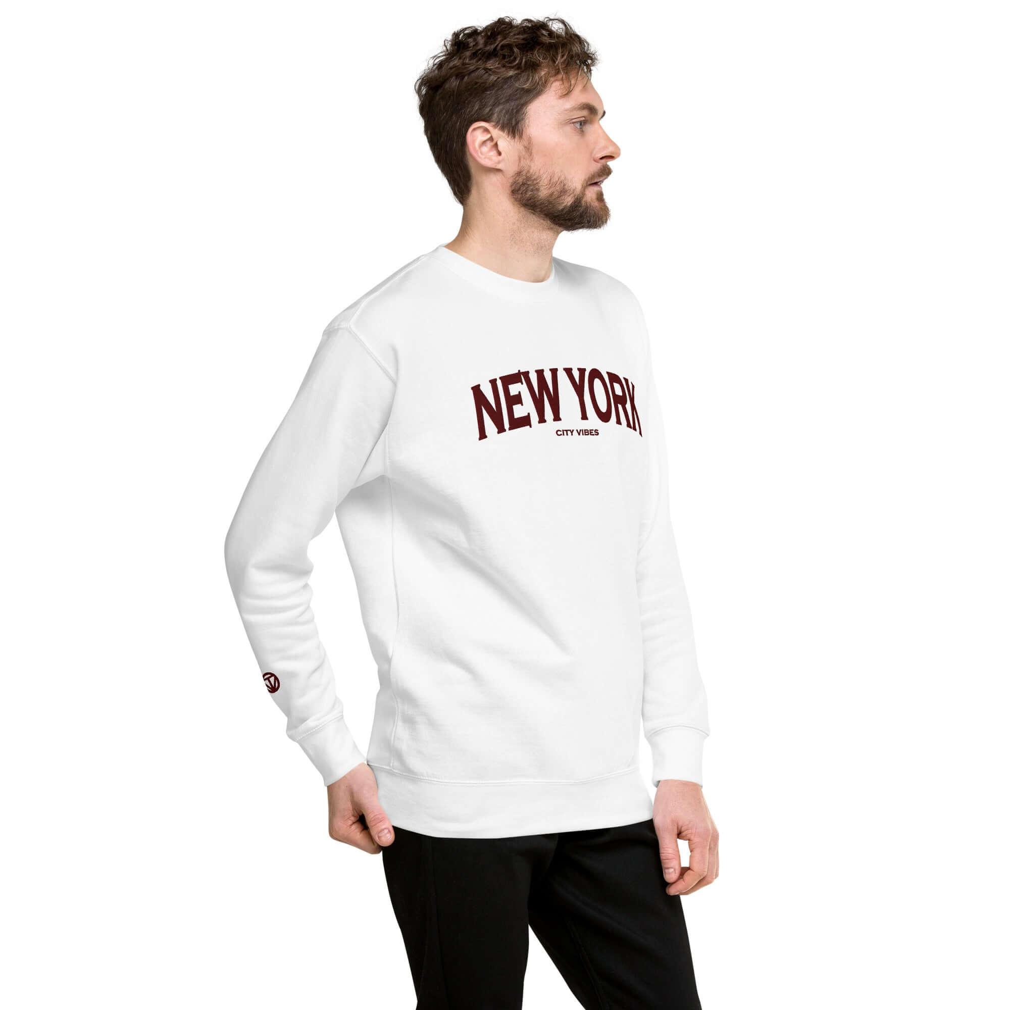 Mann in weißem Sweatshirt mit weinrotem New York Aufdruck und schwarzen Hosen