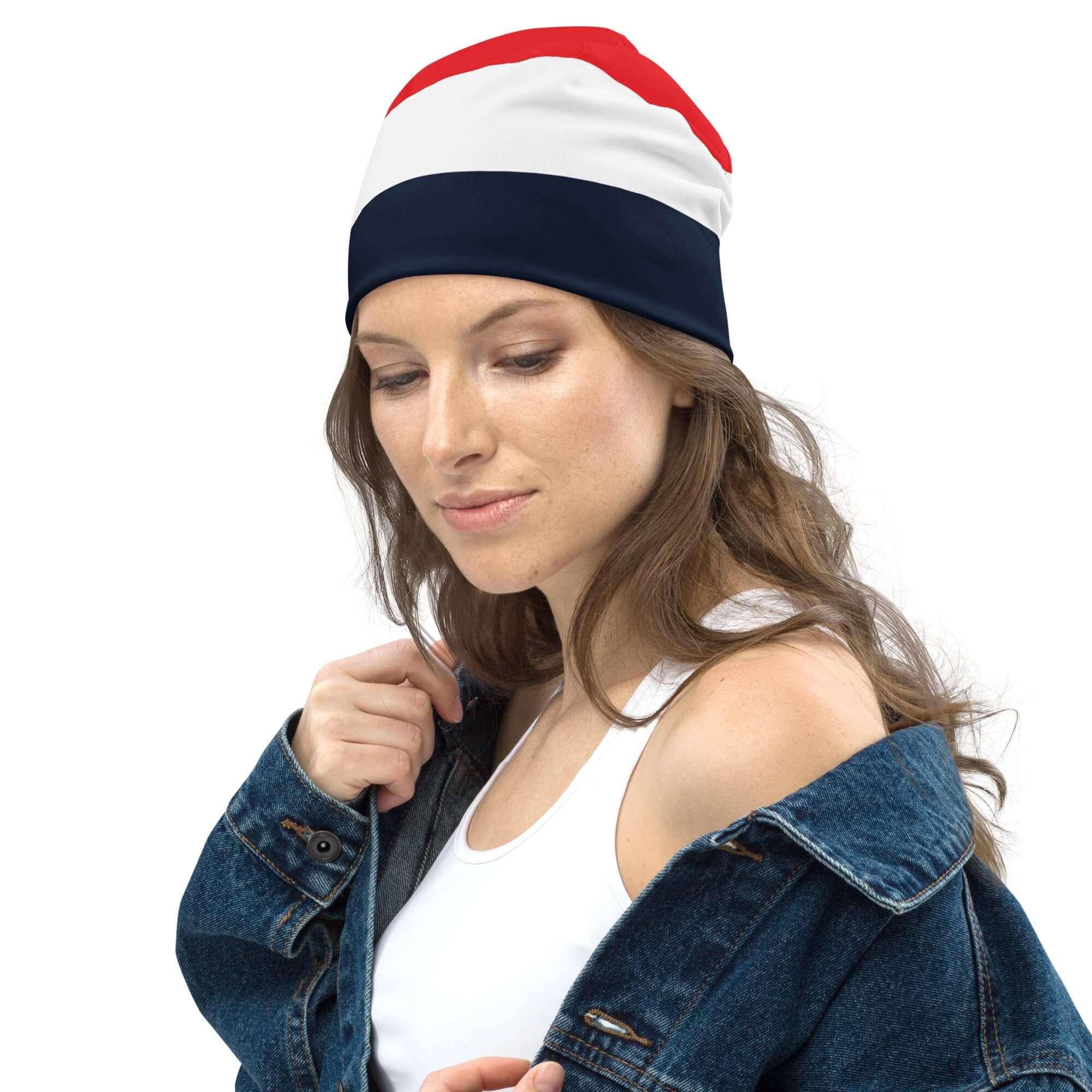 Frau mit dreifarbiger Beanie Mütze in Rot, Weiß und Dunkelblau, Jeansjacke, weißer Hintergrund