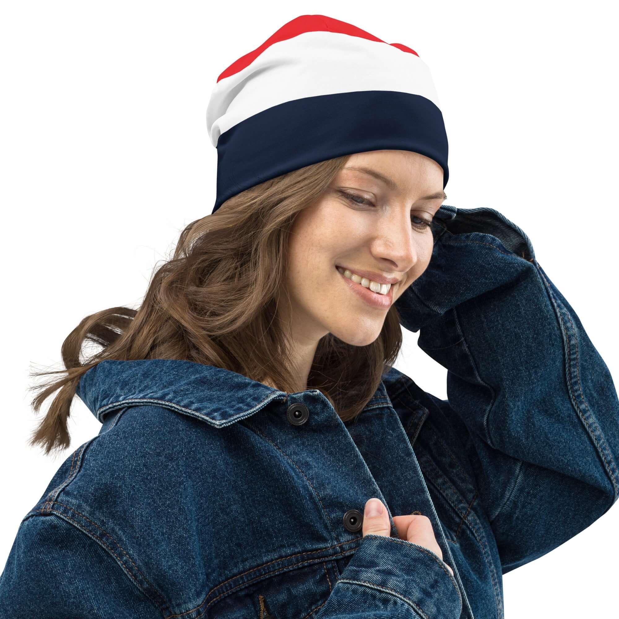 Frau mit dreifarbiger Beanie-Mütze in Rot, Weiß und Dunkelblau, Jeansjacke, weißer Hintergrund