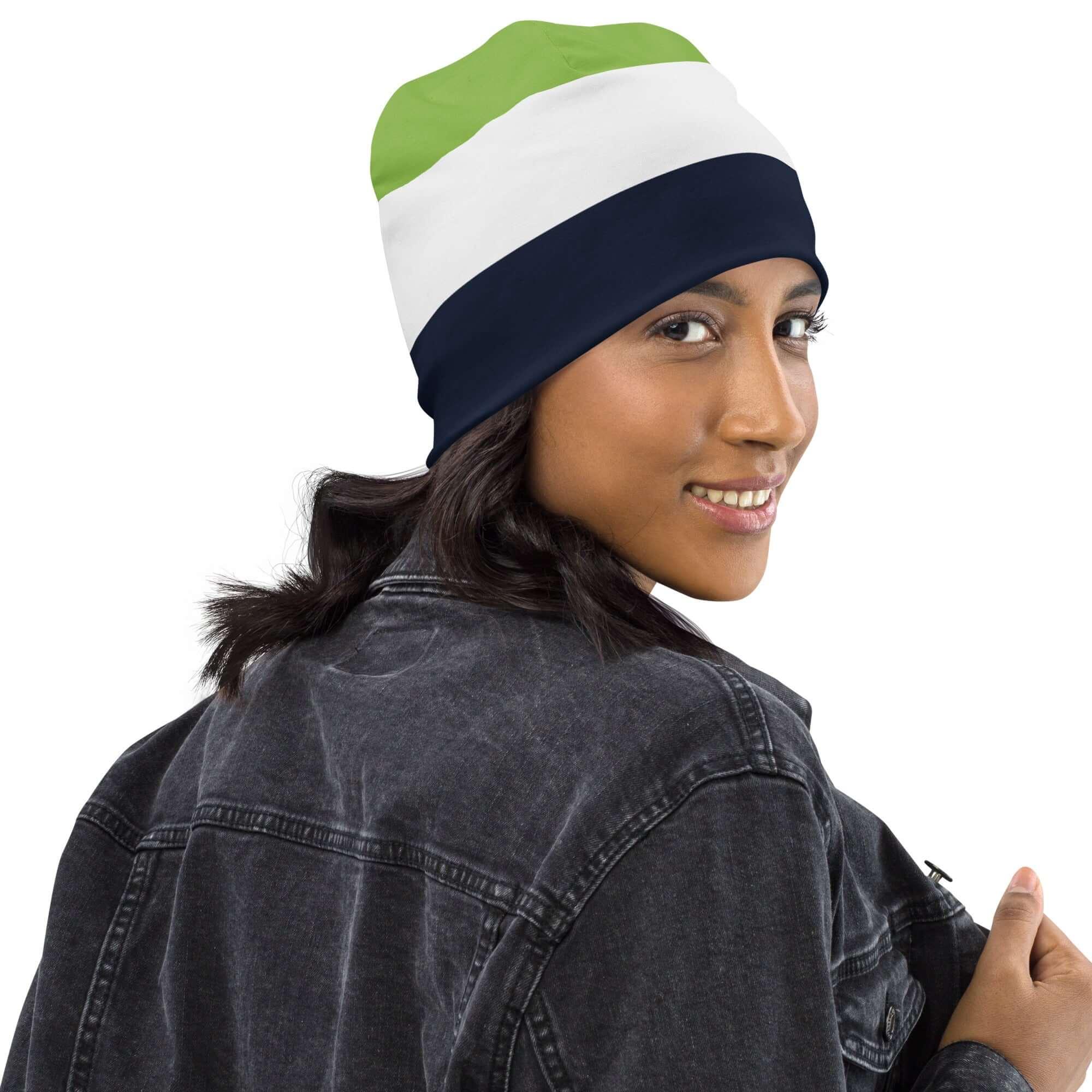 Frau mit gestreifter Beanie-Mütze in Grün, Weiß und Dunkelblau, Jeansjacke, weißer Hintergrund