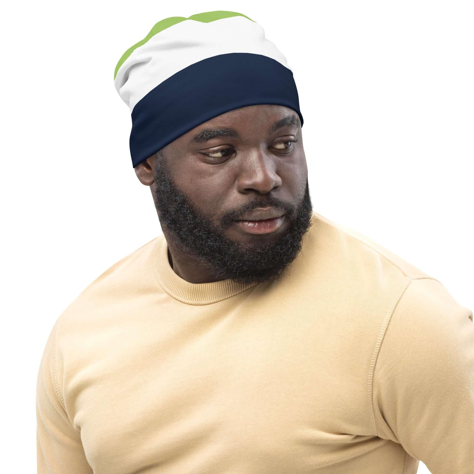 Mann mit dreifarbiger Beanie in Weiß, Blau und Grün, vor weißem Hintergrund