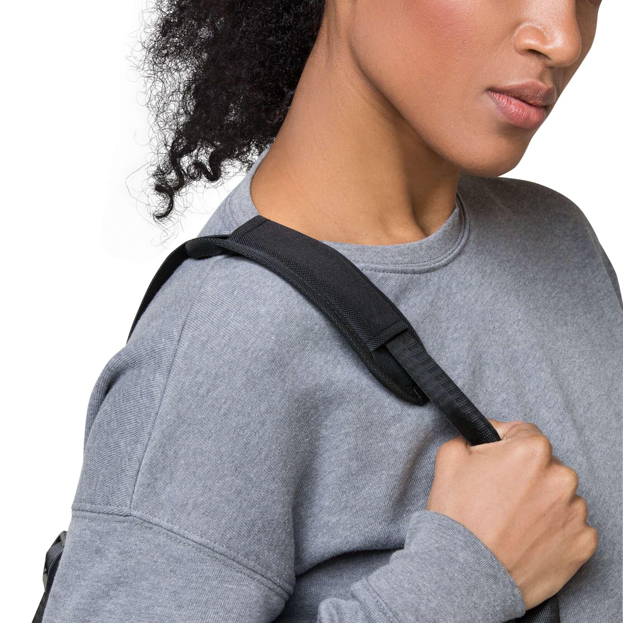 Frau mit grauem Sweatshirt trägt schwarze Duffle-Bag auf der Schulter, Nahaufnahme