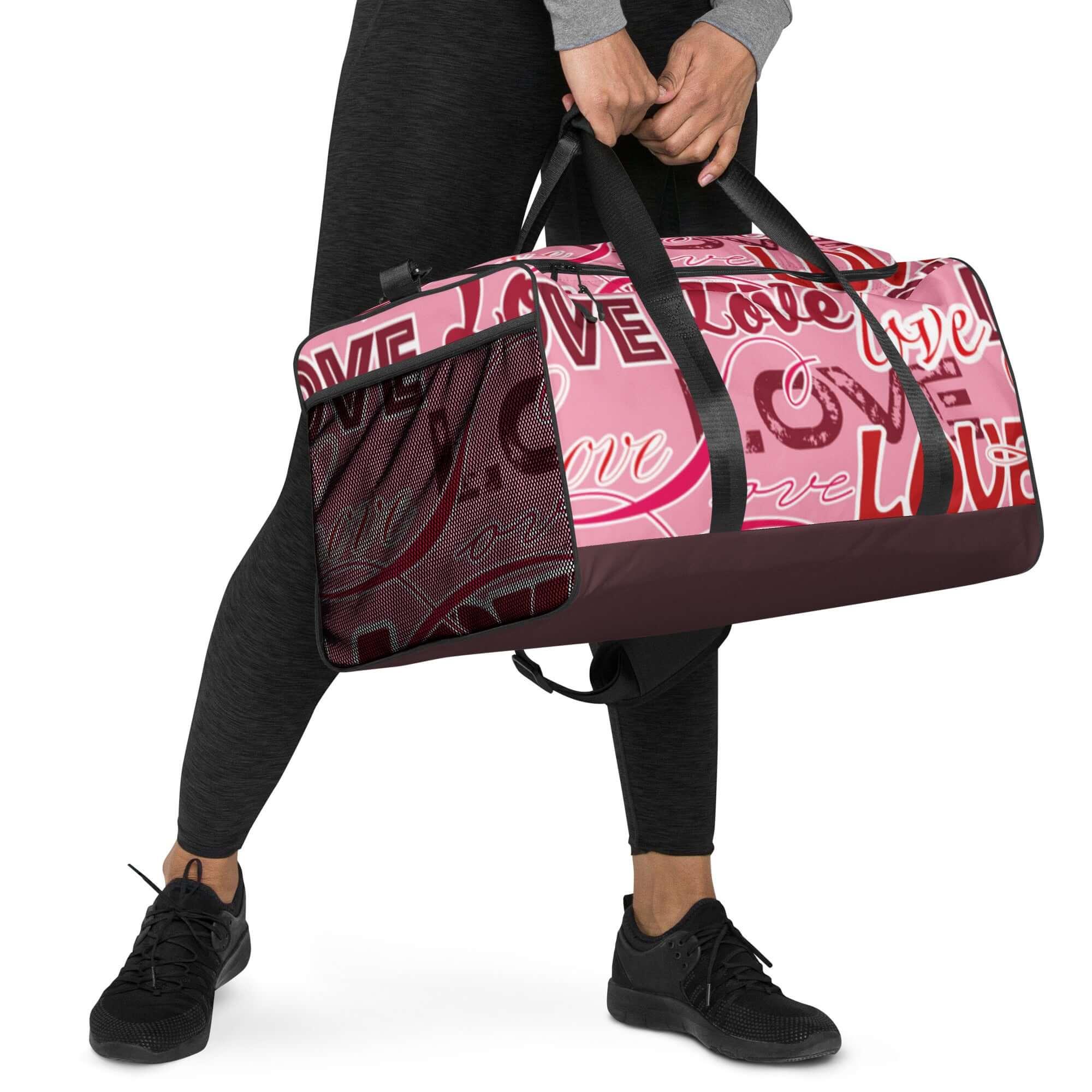 Sporttasche rosa mit schwarzem Griff, LOVE-Schriftzug, Frau in Sportkleidung hält Tasche