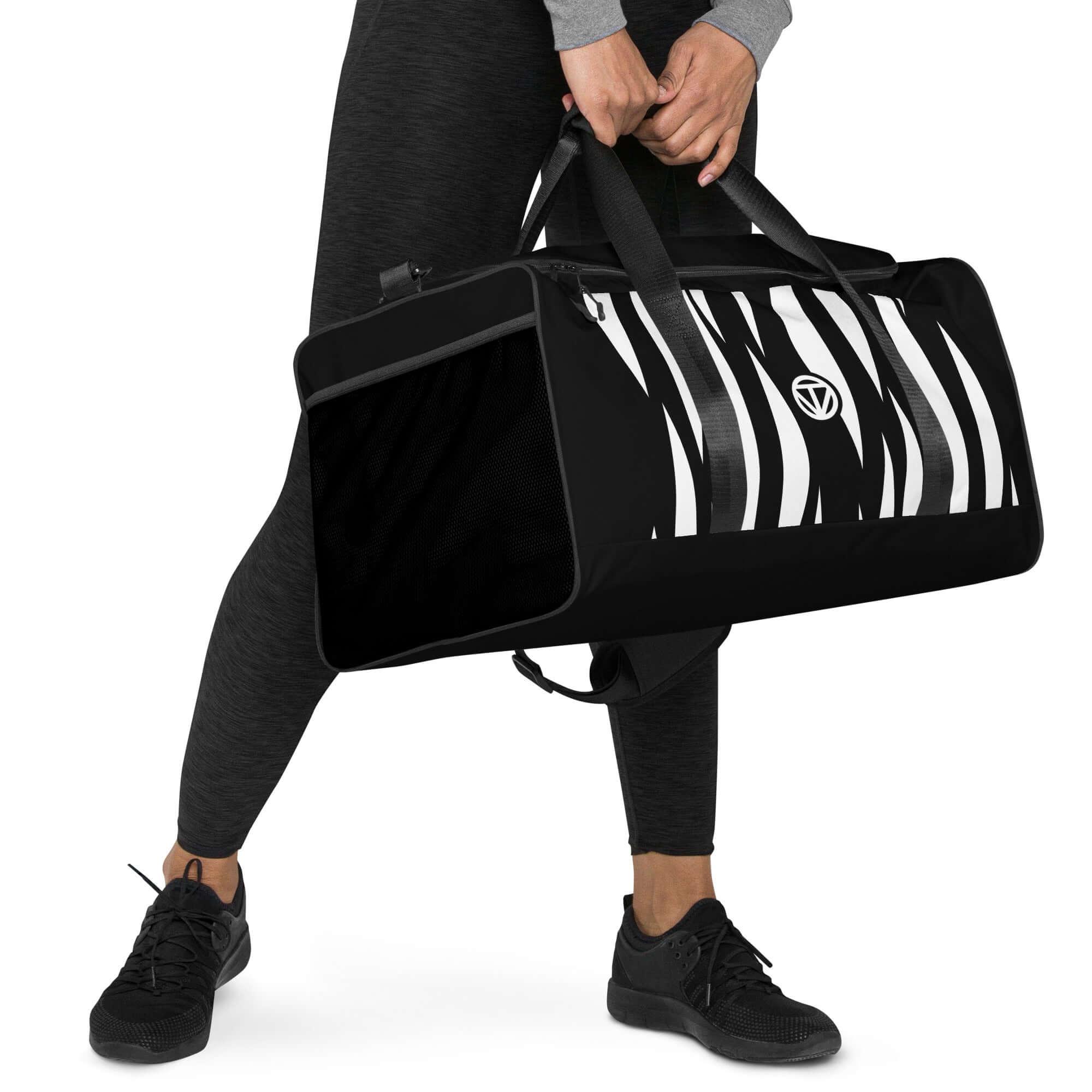 Schwarze Sporttasche mit Zebrastreifenmuster, Frau in Sportkleidung hält sie in der Hand