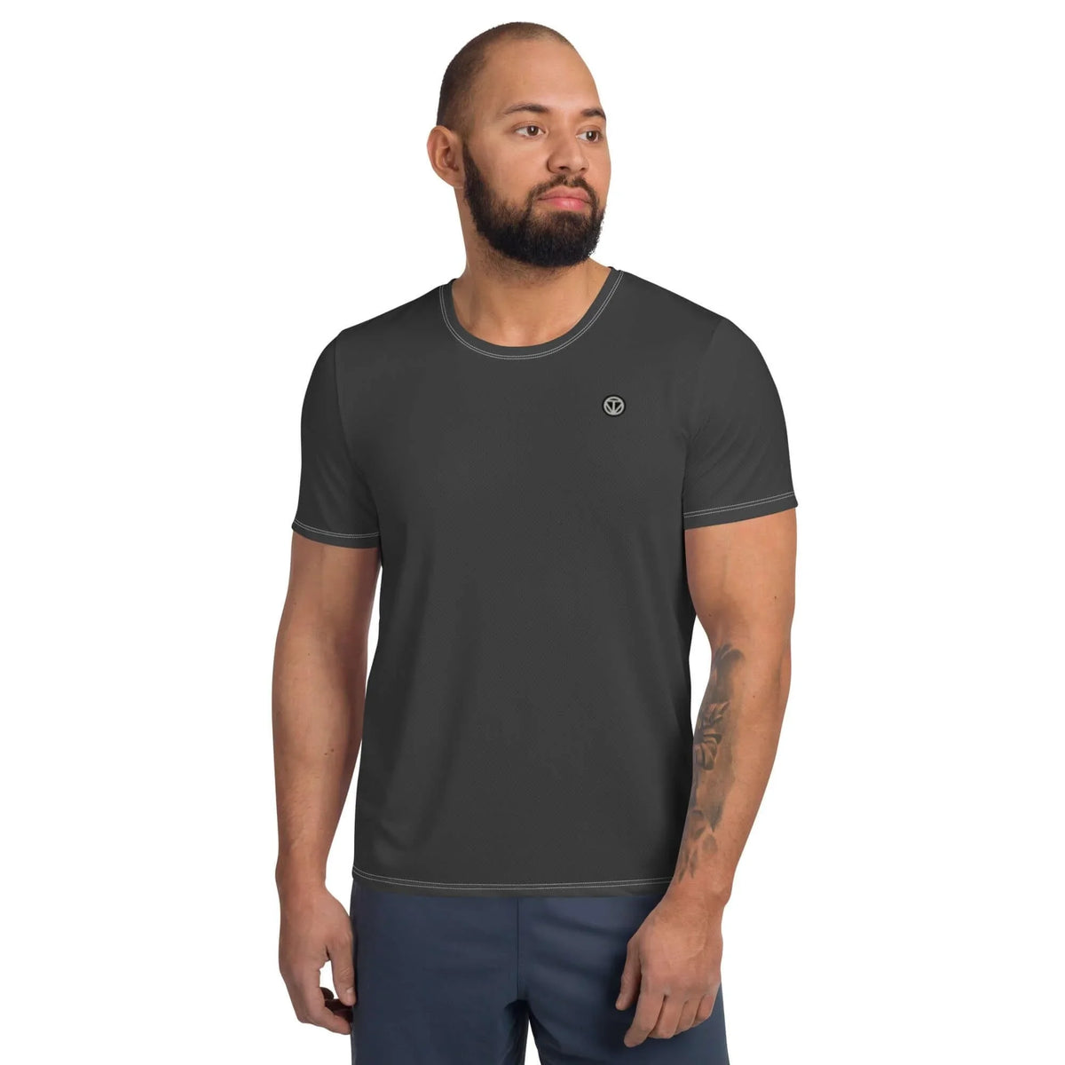 Mann mit Bart trägt ein dunkelgraues, kurzärmeliges T-Shirt mit kleinem Logo auf der Brust