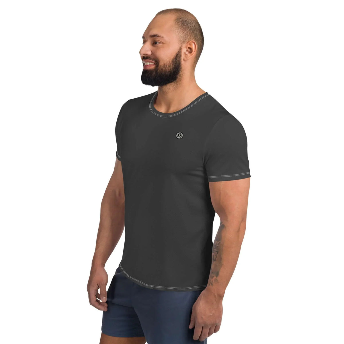 Muskulöser Mann in einem schlichten, dunkelgrauen T-Shirt mit kleinem Logo auf der Brust.