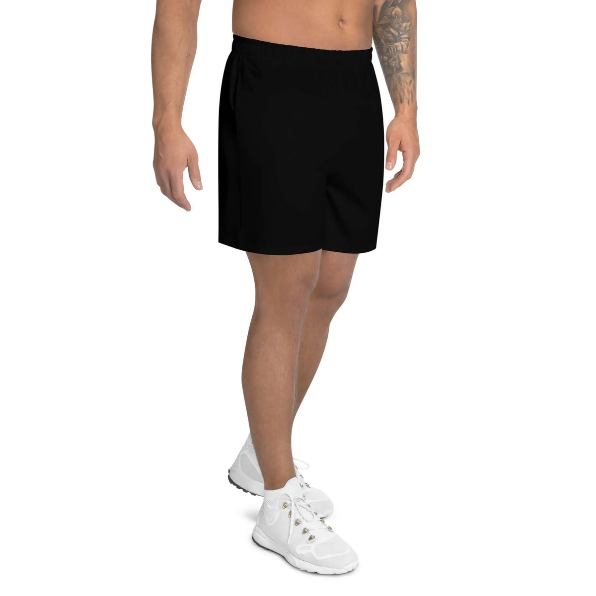 Mann trägt schwarze Sportshorts und weiße Sneaker vor weißem Hintergrund