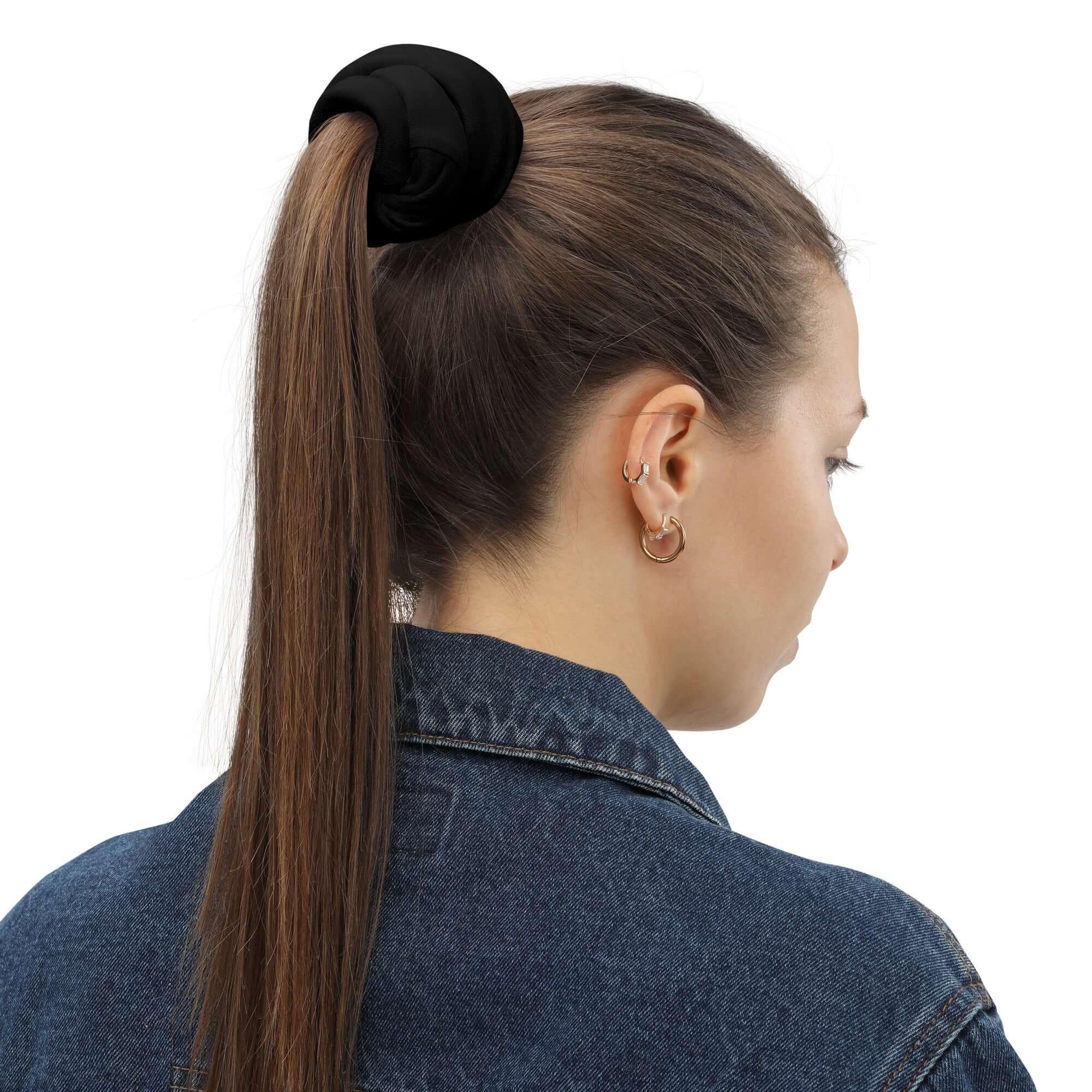Frau mit braunen Haaren, Zopfgummi und Jeansjacke von hinten, weißer Hintergrund