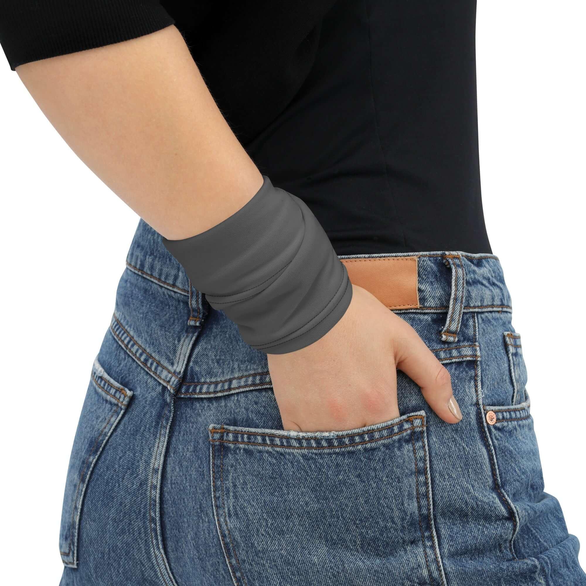 Frau mit schwarzem Oberteil, Jeans und grauem Multifunktionstuch am Handgelenk