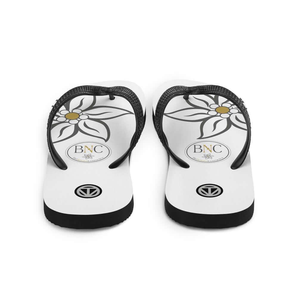 Weiße Flip-Flops mit floralem Muster und BNC-Logo auf der Sohle.