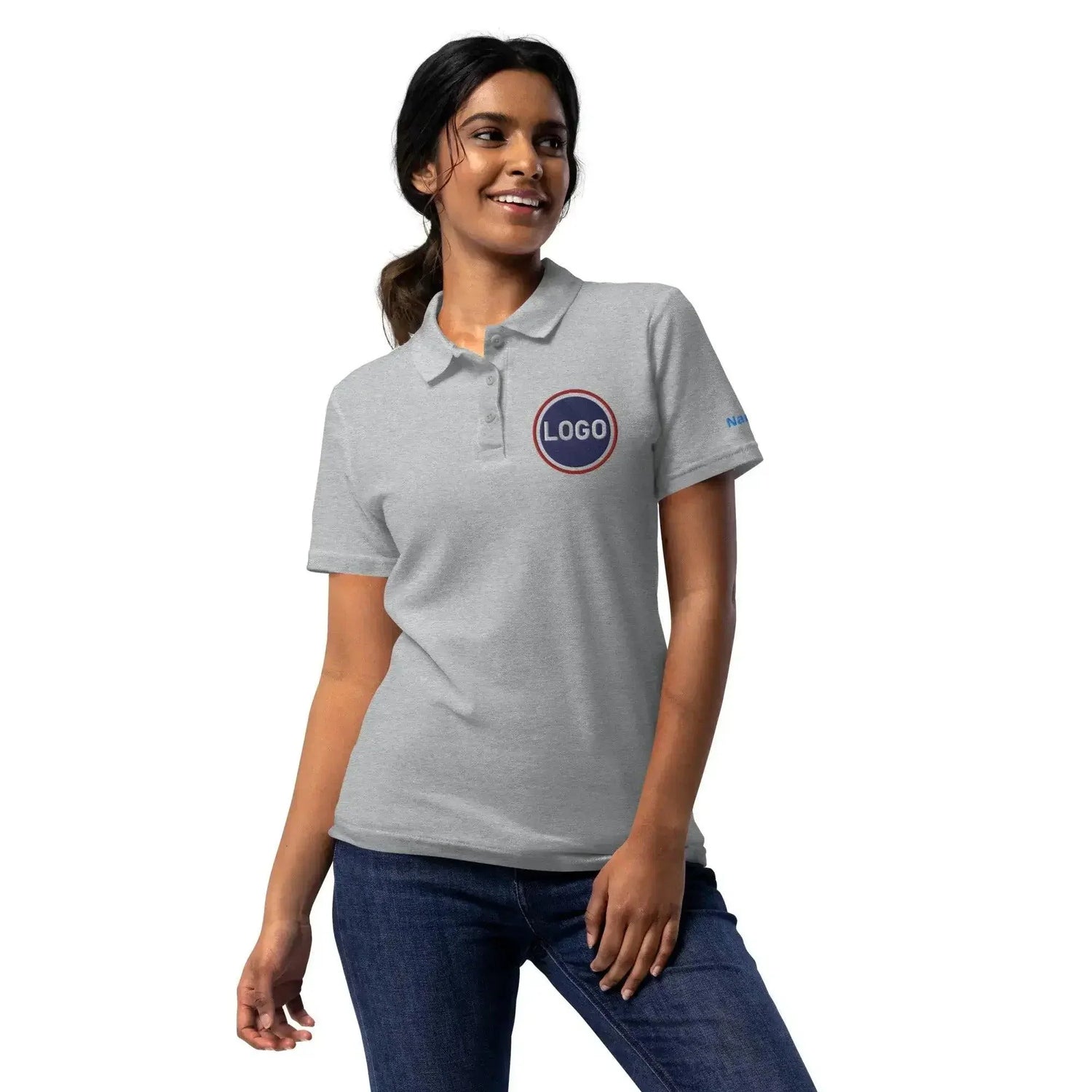 Frau trägt graues Polo-Shirt mit aufgedrucktem Logo, Jeans, weißer Hintergrund.