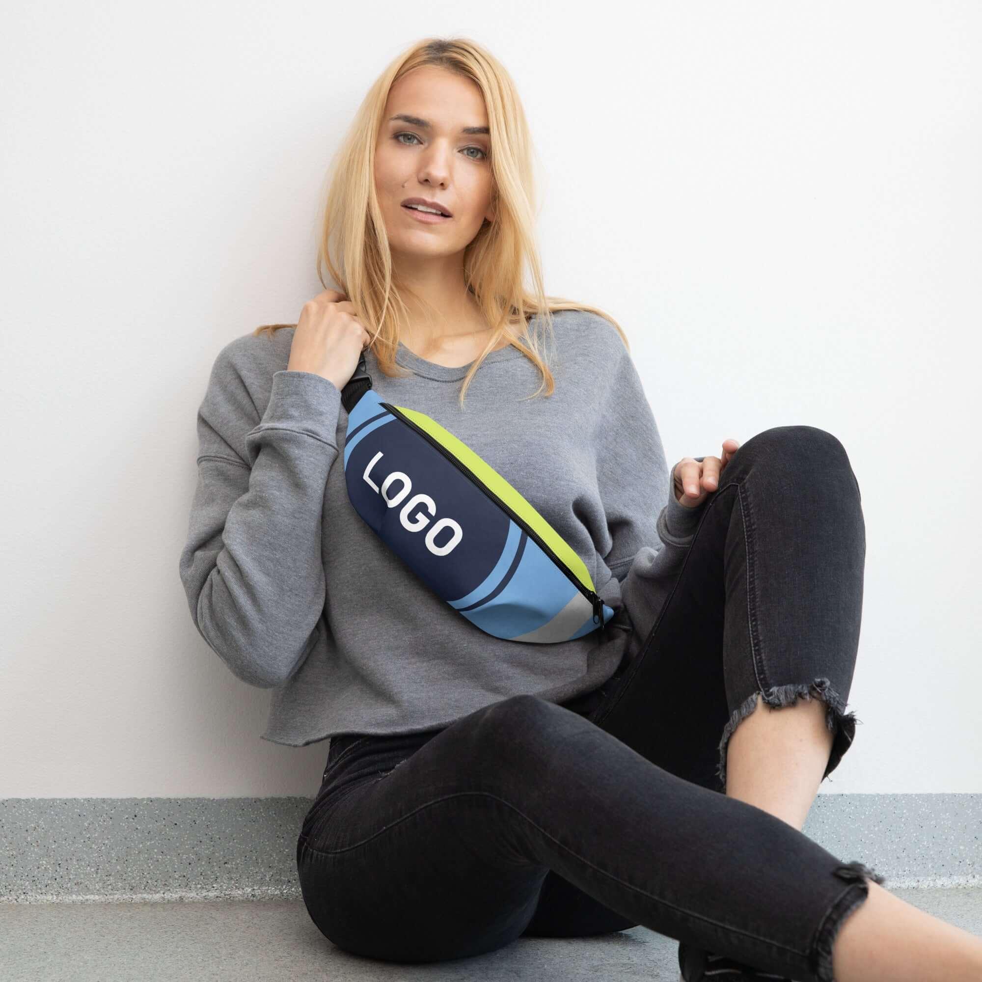 Frau mit bedruckter Bauchtasche im modernen Design sitzt leger an weißer Wand