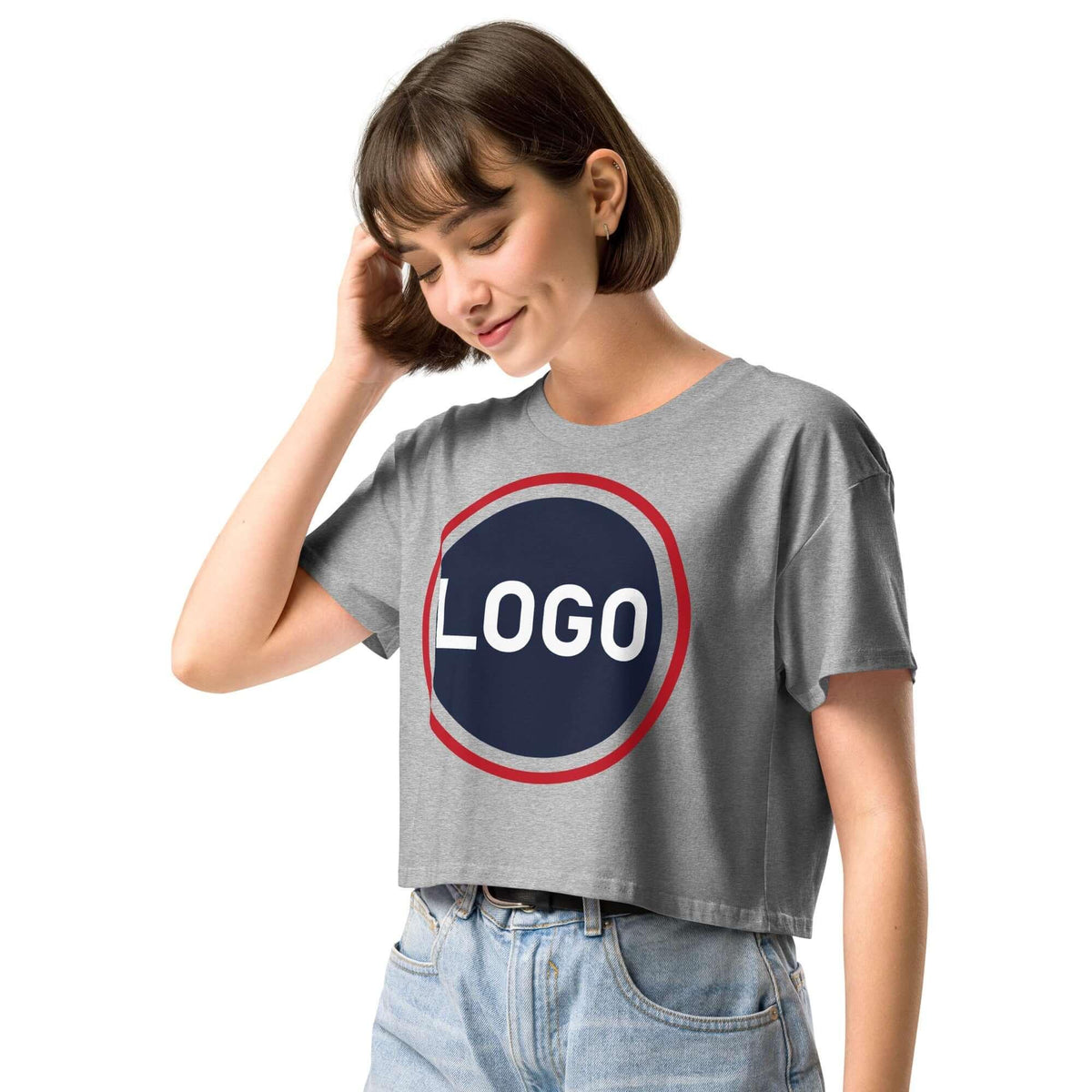 Frau in einem grauen, kurz geschnittenen T-Shirt mit rundem Logo-Print auf weißem Hintergrund