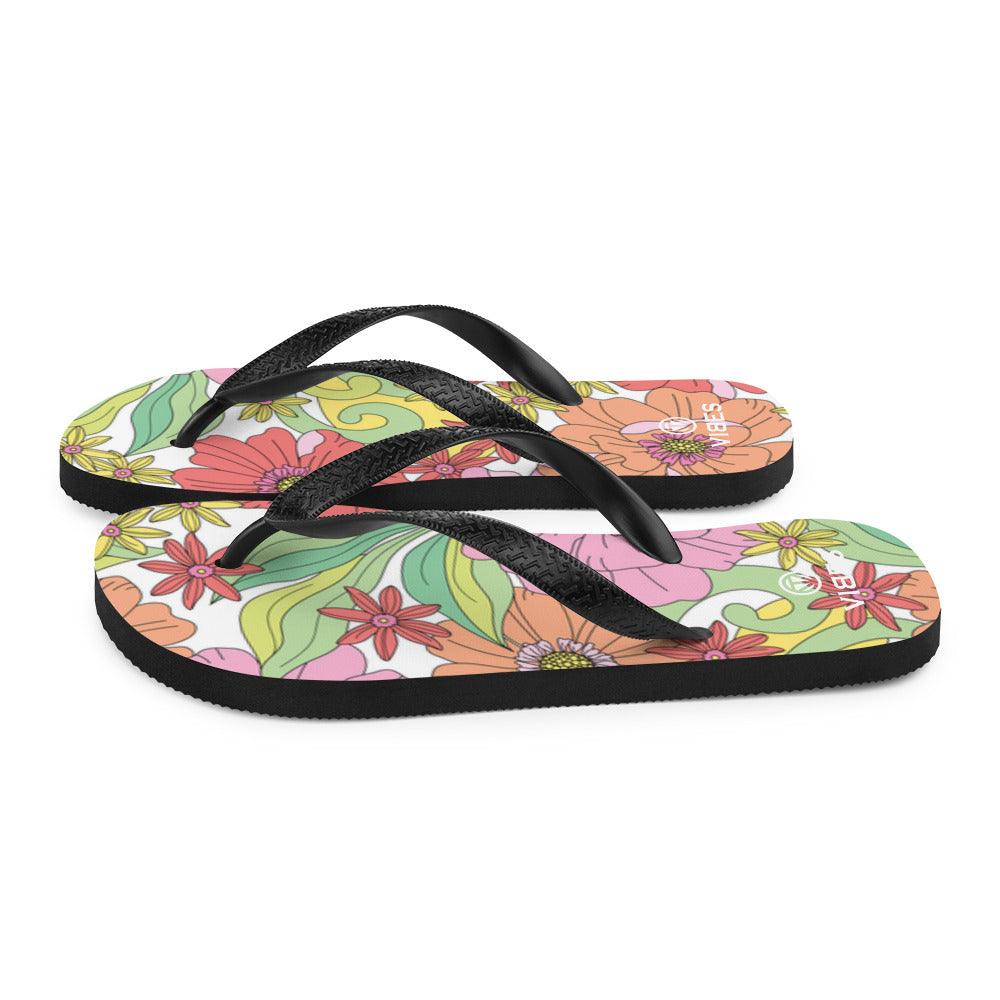 Bunte Flip-Flops mit geblümtem Muster und schwarzen Riemen auf weißem Hintergrund