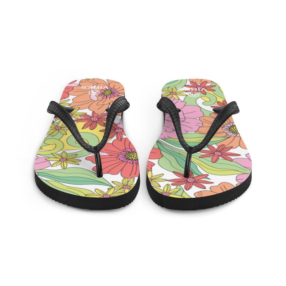 Bunte Flip-Flops mit Blumenmuster und schwarzen Riemen auf weißem Hintergrund