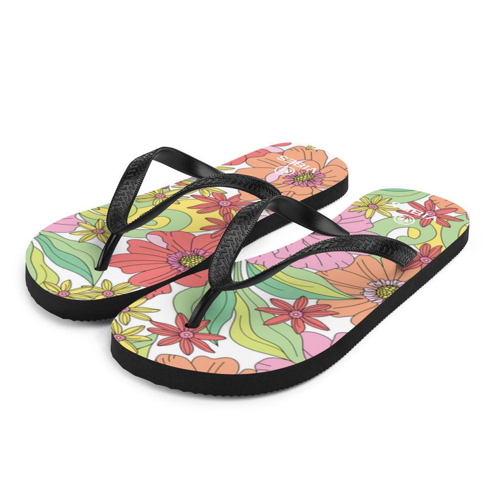 Bunte Flip-Flops mit floralem Muster und schwarzen Riemen auf weißem Hintergrund