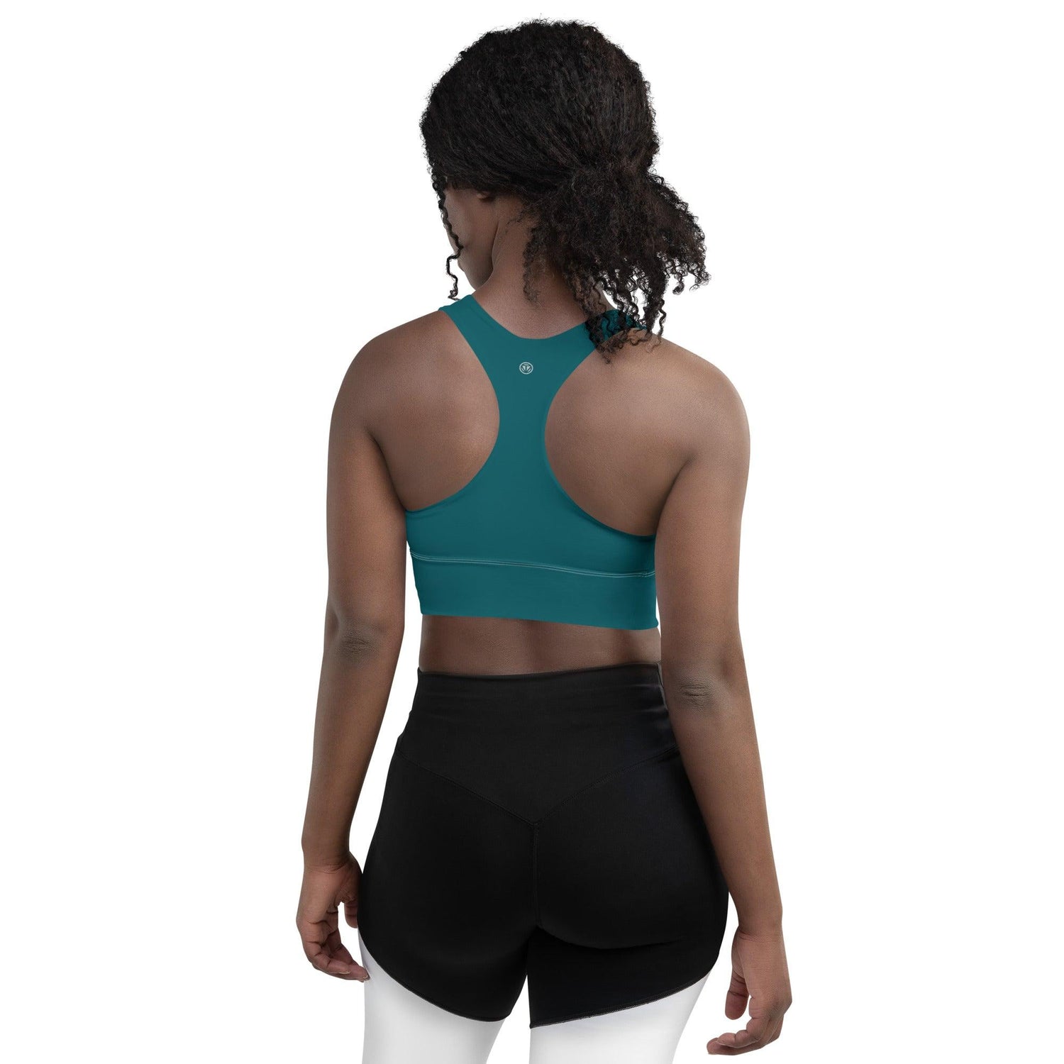 Frau mit blau-grünem langen Sport-BH von hinten, trägt schwarze Shorts, Studioaufnahme