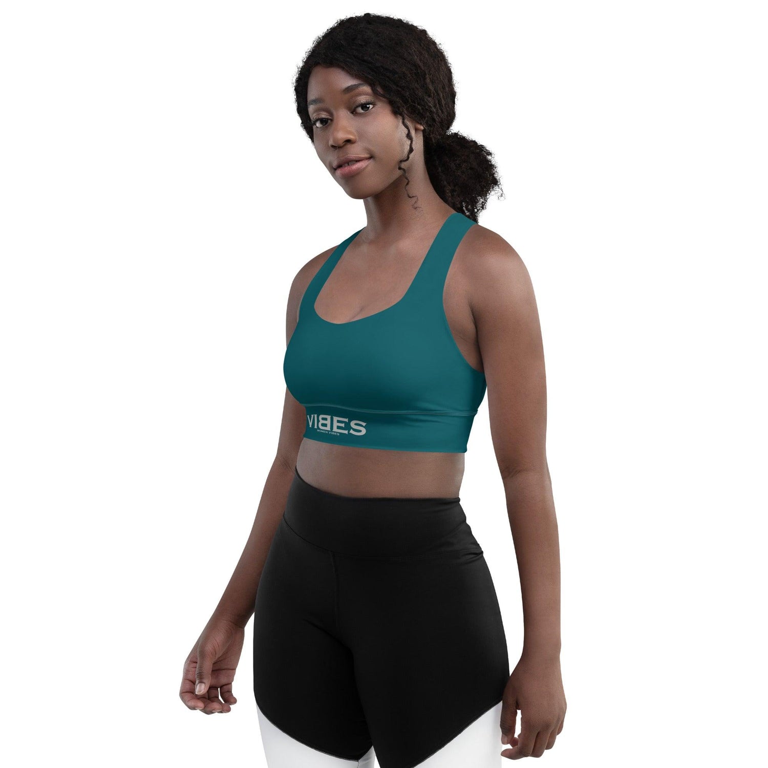 Frau trägt blauen Sport-BH mit VIBES-Logo und schwarze Sportleggings vor weißem Hintergrund