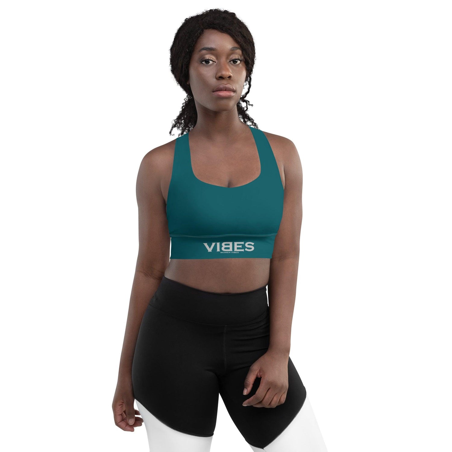 Frau trägt blauen VIBES Sport-BH und schwarze Leggings vor weißem Hintergrund