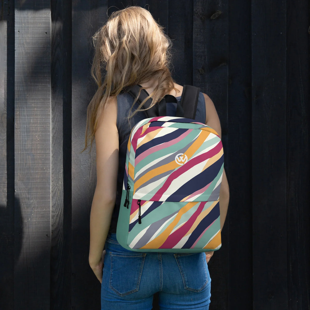 Frau von hinten mit bunt gestreiftem CREWILD Rucksack vor dunkler Holzwand