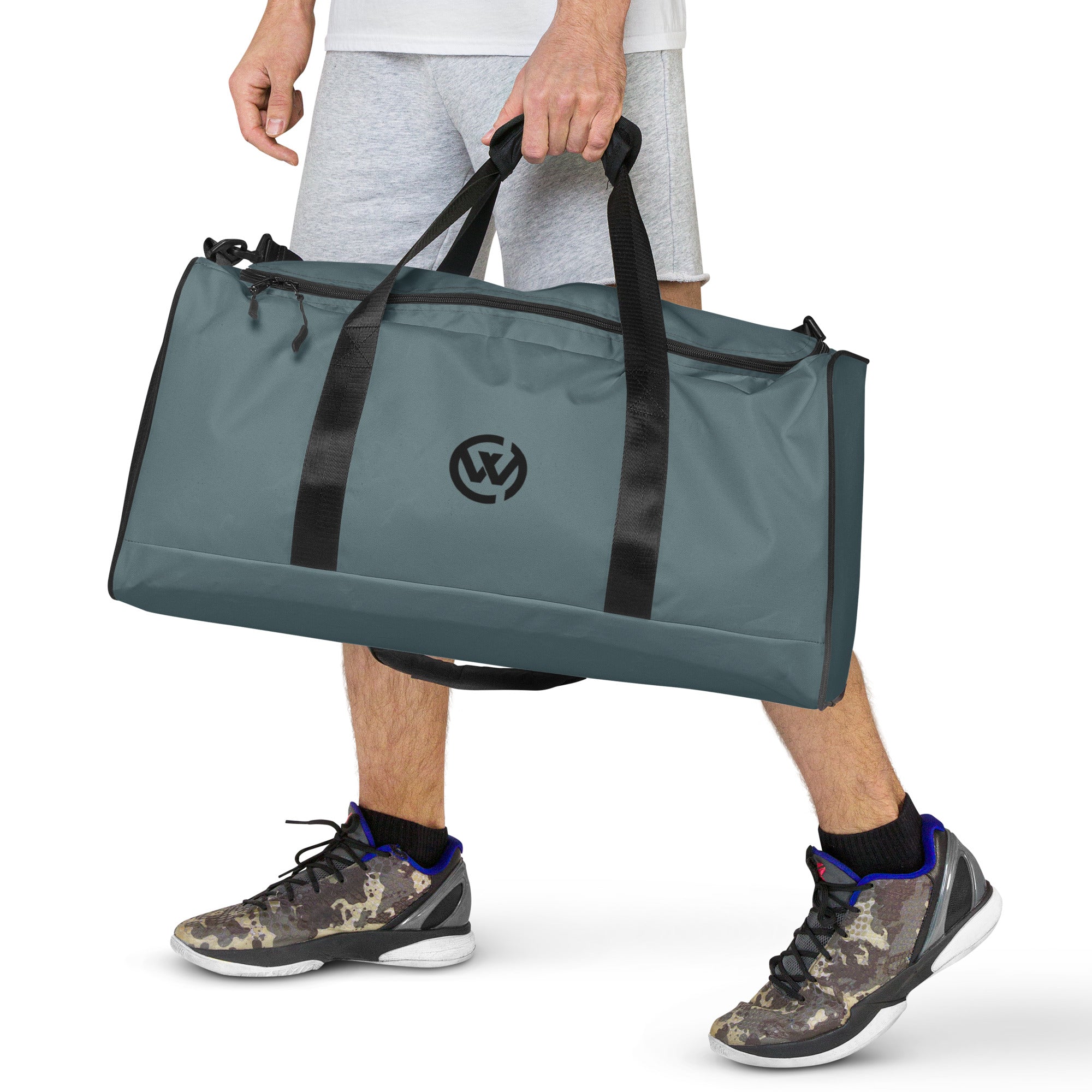 Person trägt eine graublaue Sporttasche mit Logo und Camouflage-Sneakern