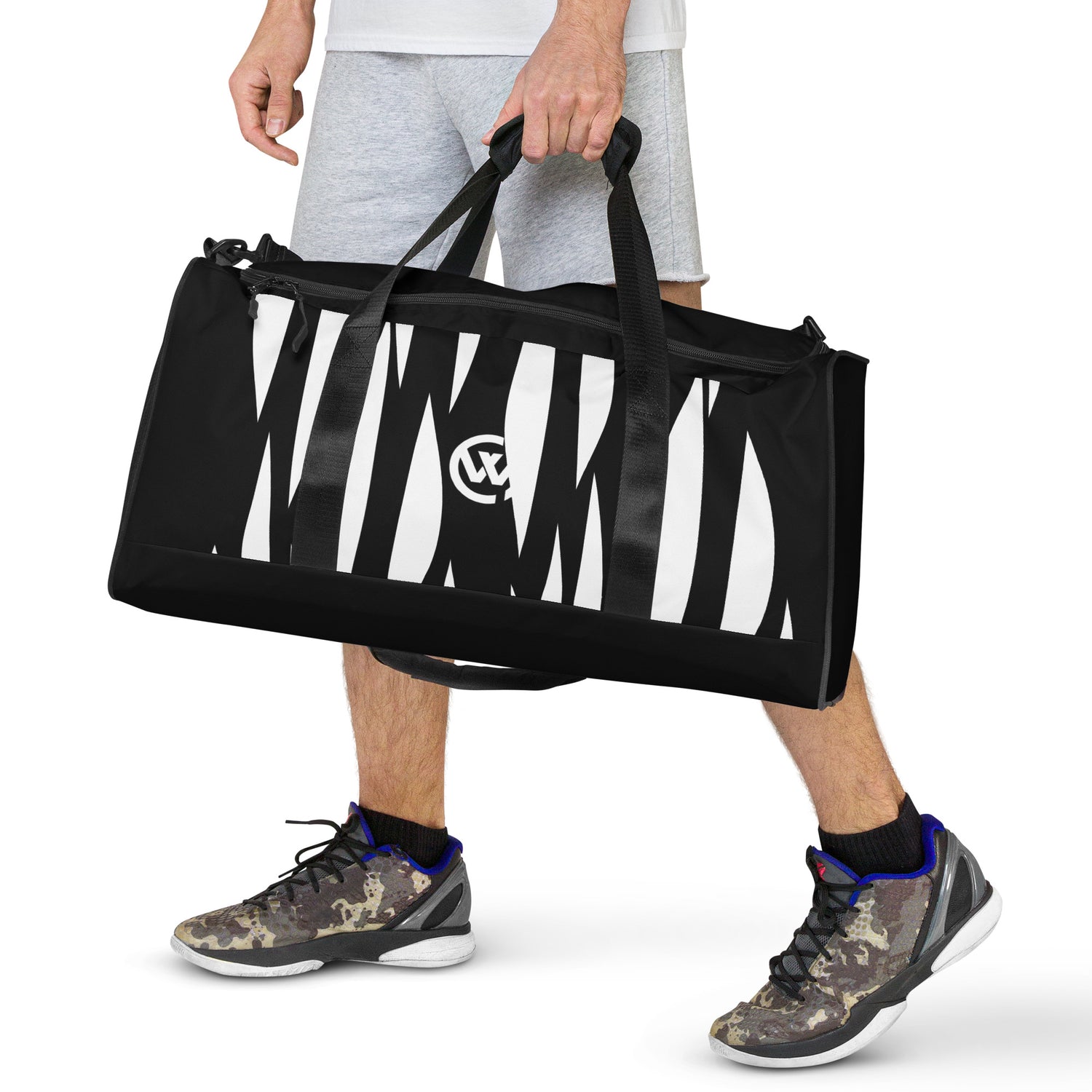 Person trägt eine schwarze Sporttasche mit weißem Streifendesign und Logo.