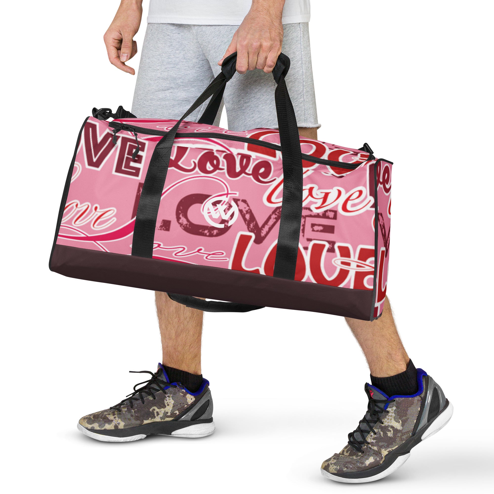 Person hält eine personalisierte rosa Sporttasche mit Love-Print und Camouflage-Sneaker.