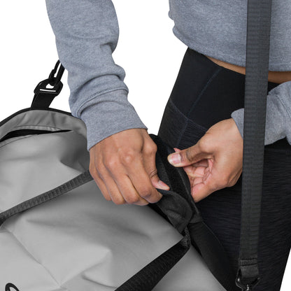 Detailansicht einer Person, die die Tasche einer grauen Sporttasche schließt.