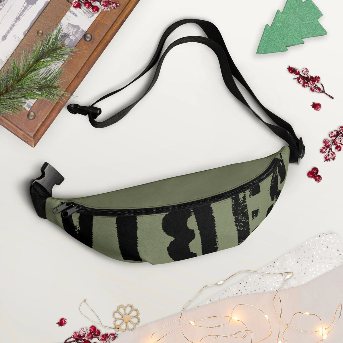 Olivgrüne Bauchtasche mit schwarzem Grafikprint auf weißem Hintergrund mit Weihnachtsdekoration