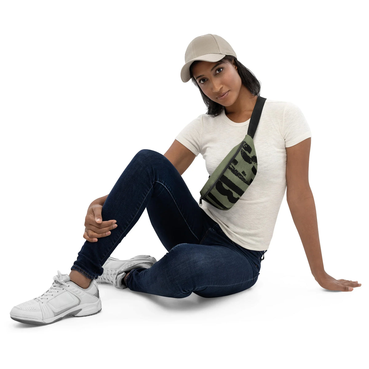 Frau mit weißem T-Shirt, dunkelblauen Jeans, weißen Sneakern und einer grün gemusterten Bauchtasche.